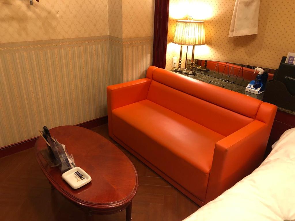 - un canapé orange et une table dans une chambre d'hôtel dans l'établissement Restay Puchi Nagasaki Club (Adult Only), à Nagasaki