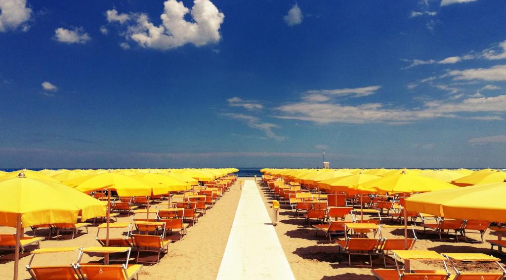 une rangée de parasols et de chaises jaunes sur une plage dans l'établissement Hotel Dante Family Spa Resort, à Cervia 93 autres photos