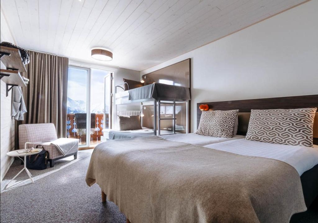 une chambre d'hôtel avec un grand lit et une chaise dans l'établissement Langley Hôtel Le Petit Prince, à L'Alpe-d'Huez