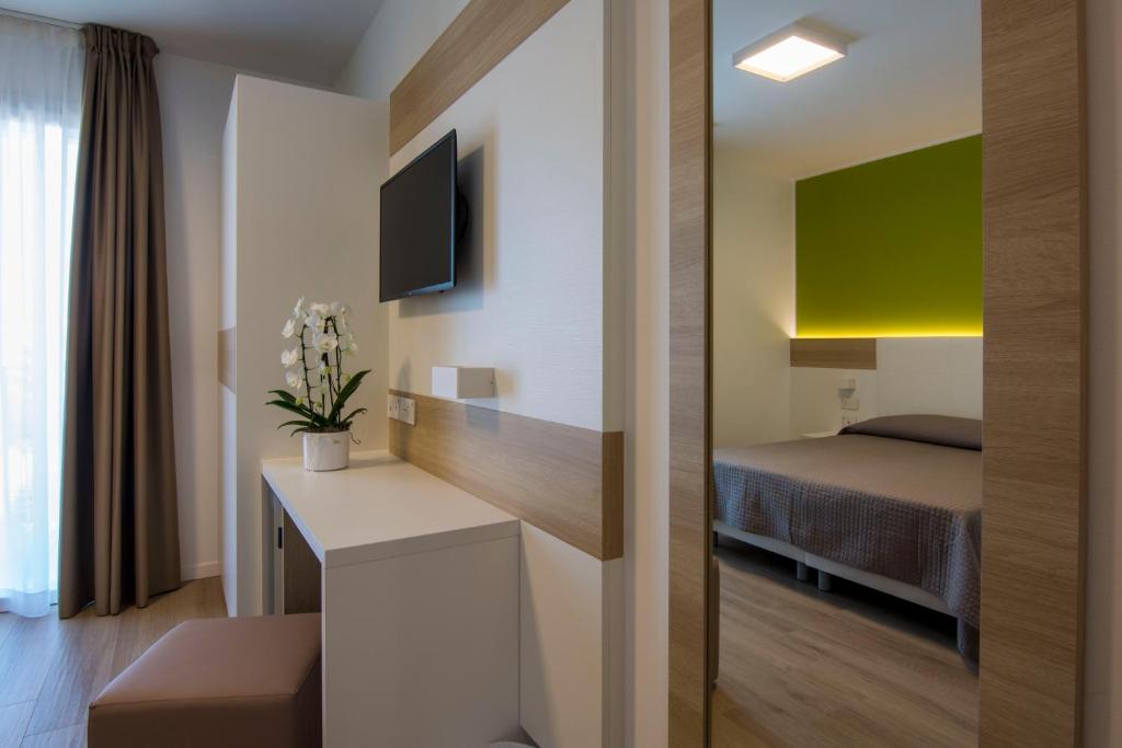 Cette chambre comprend un lit et un bureau avec une télévision. dans l'établissement Almalux Jesolo Wellness & Spa 3 stelle superior, à Lido di Jesolo