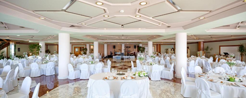 une salle de banquet avec des tables et des chaises blanches dans l'établissement Grand Hotel Pianeta Maratea Resort, à Maratea 139 autres photos