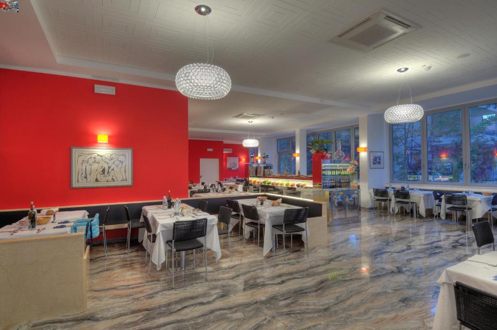 un restaurant avec des tables et des chaises et un mur rouge dans l'établissement Hotel Firenze, à Bibione