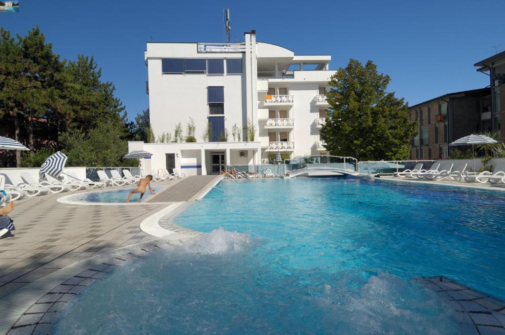 une femme se tient dans une piscine en face d'un bâtiment dans l'établissement Hotel Firenze, à Bibione