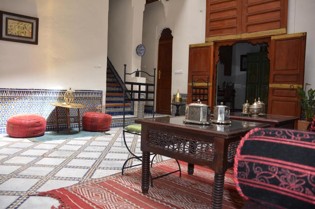 - un salon avec une table, des chaises et des escaliers dans l'établissement Riad Dezayn, à Fès