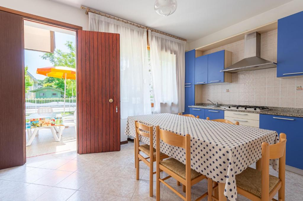 une cuisine avec une table et des chaises et une cuisine avec des armoires bleues dans l'établissement Margherita Family Apartments, à Cavallino-Treporti
