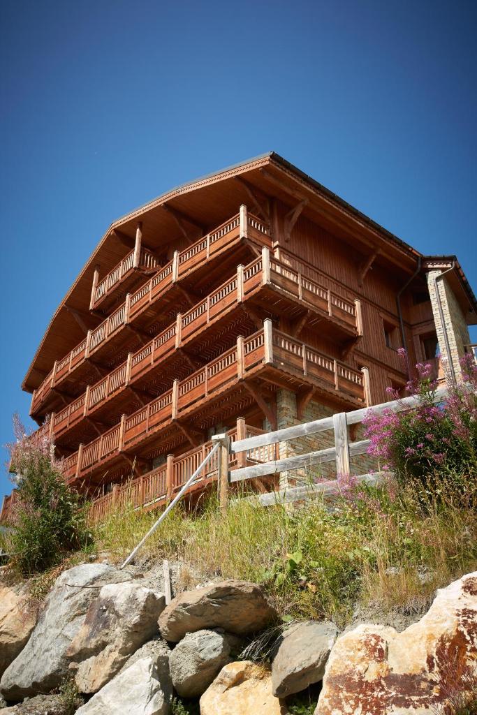 un grand bâtiment en bois au sommet d'une colline dans l'établissement CGH Résidences & Spas les Chalets du Soleil Contemporain, aux Menuires