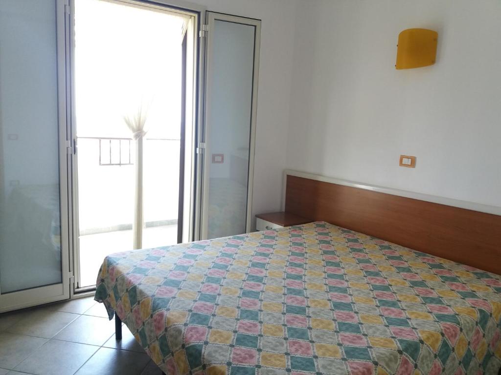 une chambre avec un lit et une grande fenêtre dans l'établissement Villa dei pini, à Vieste