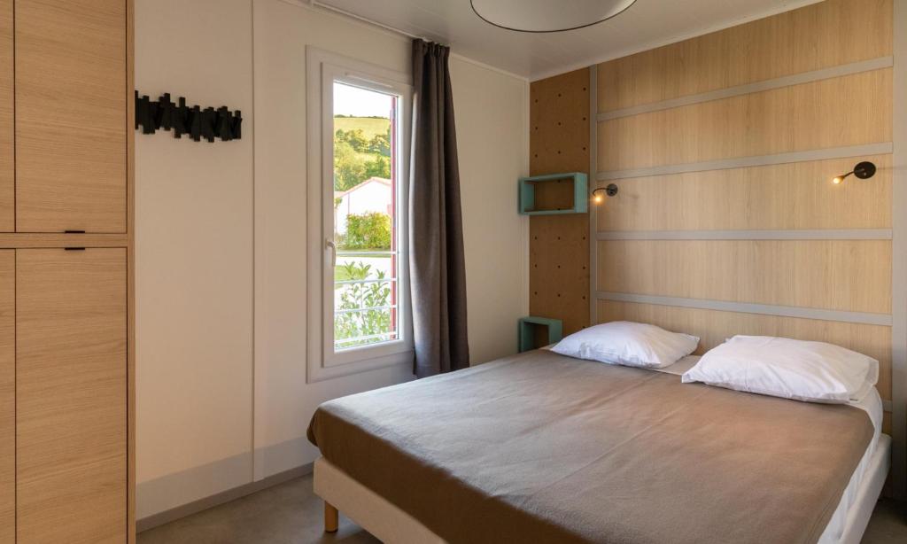 une chambre avec un lit et une fenêtre dans l'établissement Domaine Chalets Larlapean, à Saint-Martin-dʼArrossa