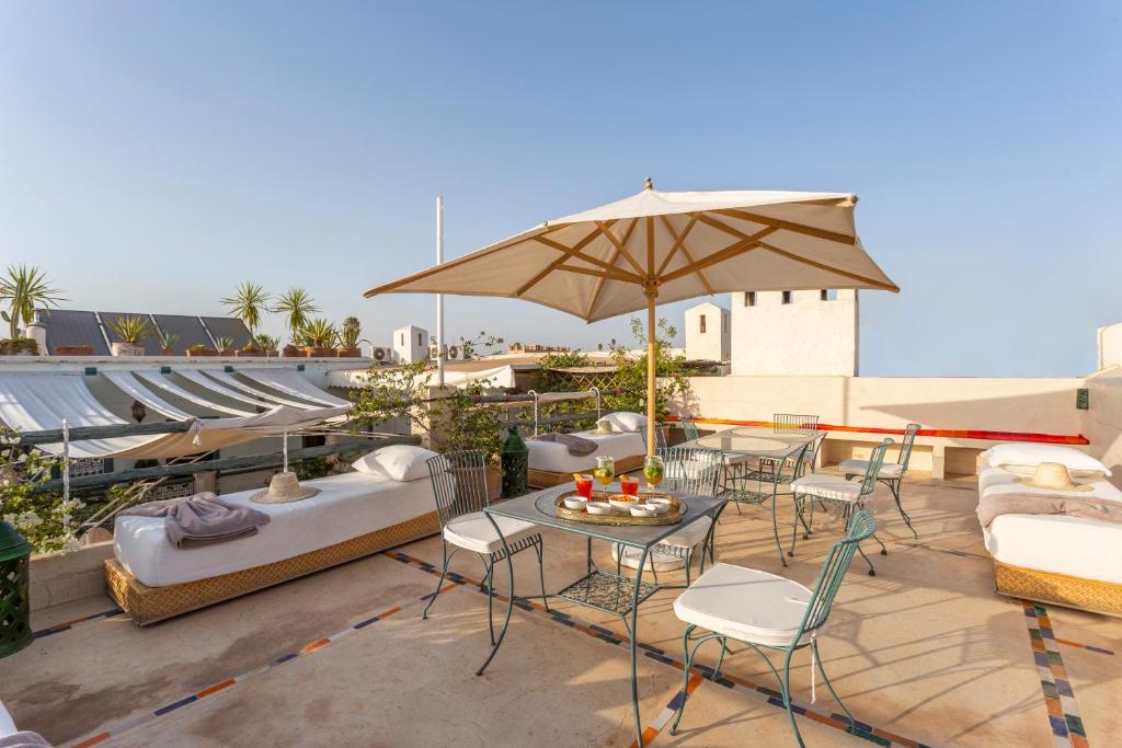 un patio avec une table, des chaises et un parasol dans l'établissement Riad Azahar, à Marrakech