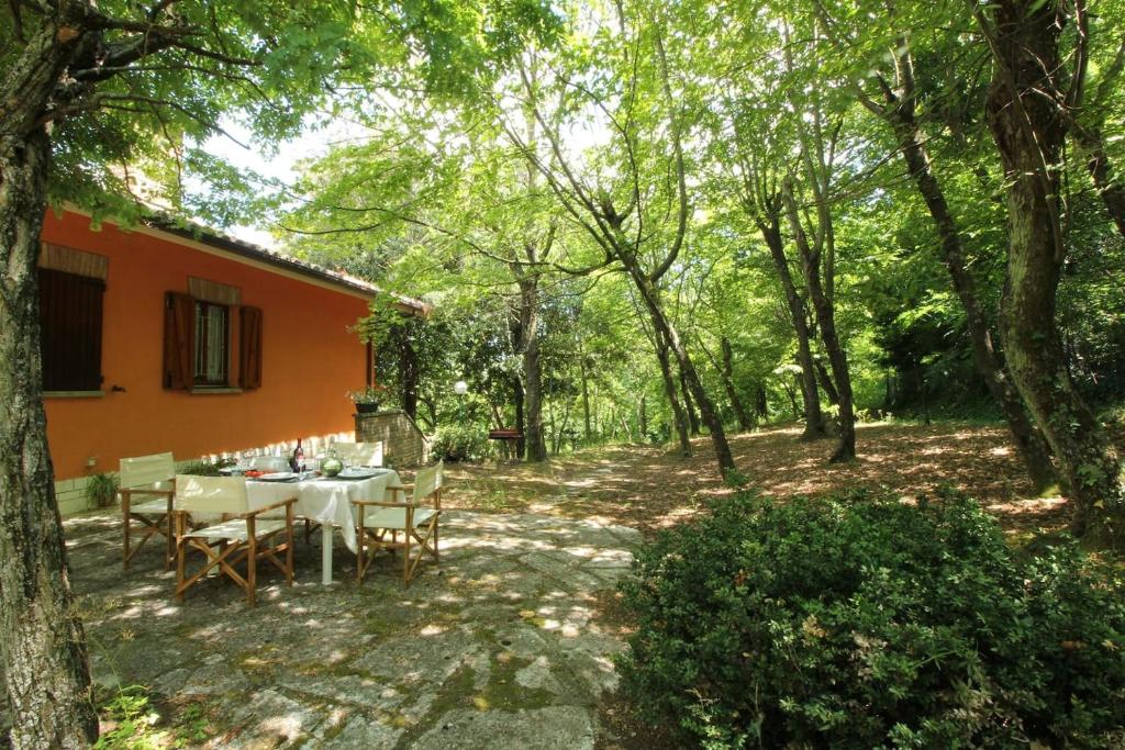 une table et des chaises dans une cour arborée dans l'établissement Villa Mombaroccio le colline di Pesaro tra mare e natura, à Mombaroccio