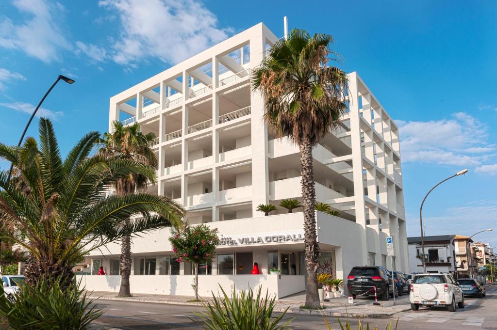 un bâtiment blanc avec des palmiers devant dans l'établissement Hotel Villa Corallo, à San Benedetto del Tronto