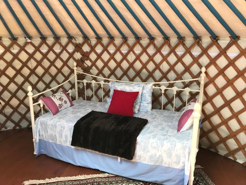 - un lit dans une yourte avec des oreillers dans l'établissement French Fields Luxury Glamping Original Mongolian Yurt, à Le-Vieux-Cérier