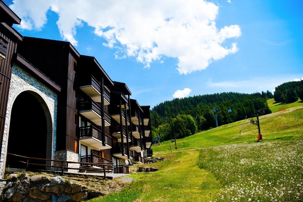 un bâtiment sur une colline à côté d'un champ herbeux dans l'établissement Your apartment near the ski lift, à Aime La Plagne