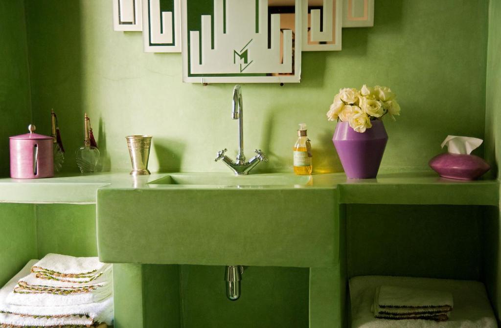 une salle de bains verte avec un lavabo et un vase de fleurs dans l'établissement Riad Le J, à Marrakech