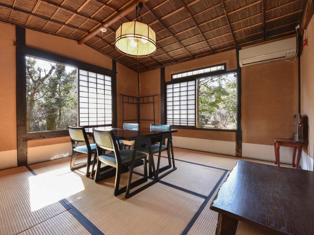 une salle à manger avec une table, des chaises et des fenêtres dans l'établissement Nagataki, à Nakatsugawa