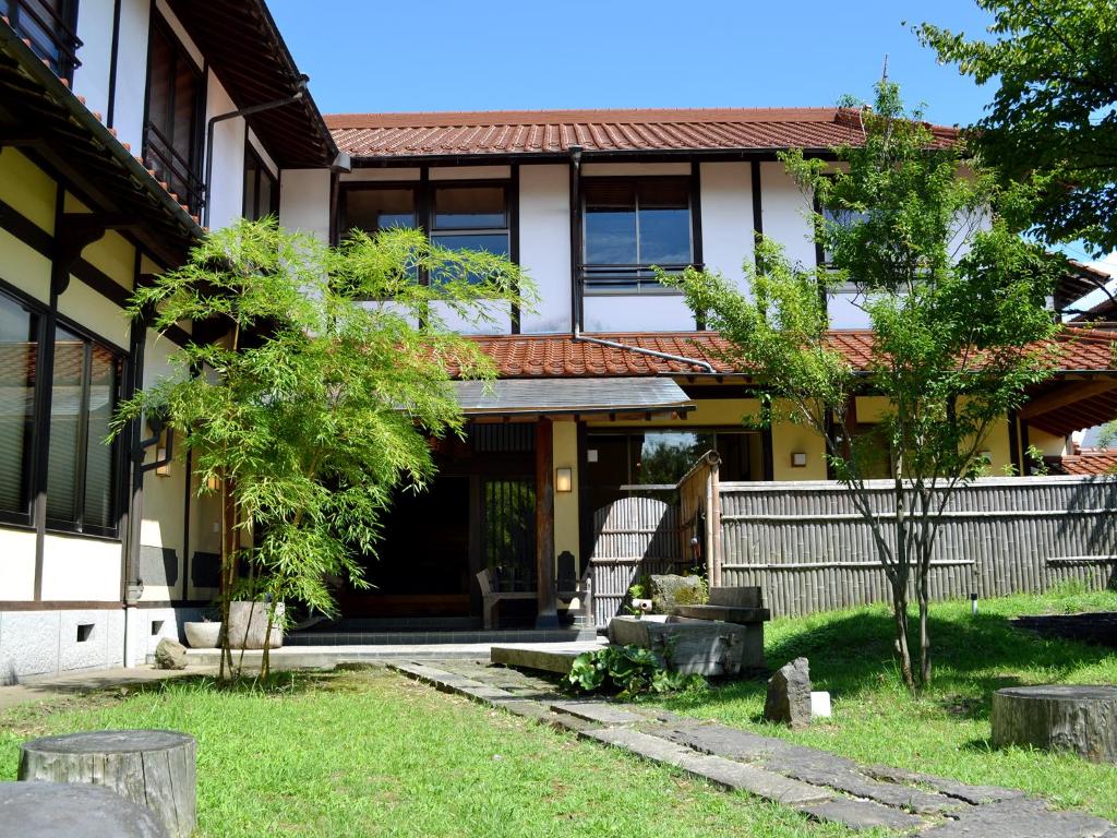 une maison avec une clôture et une cour dans l'établissement Tabinoyado Asonoyu, à Aso