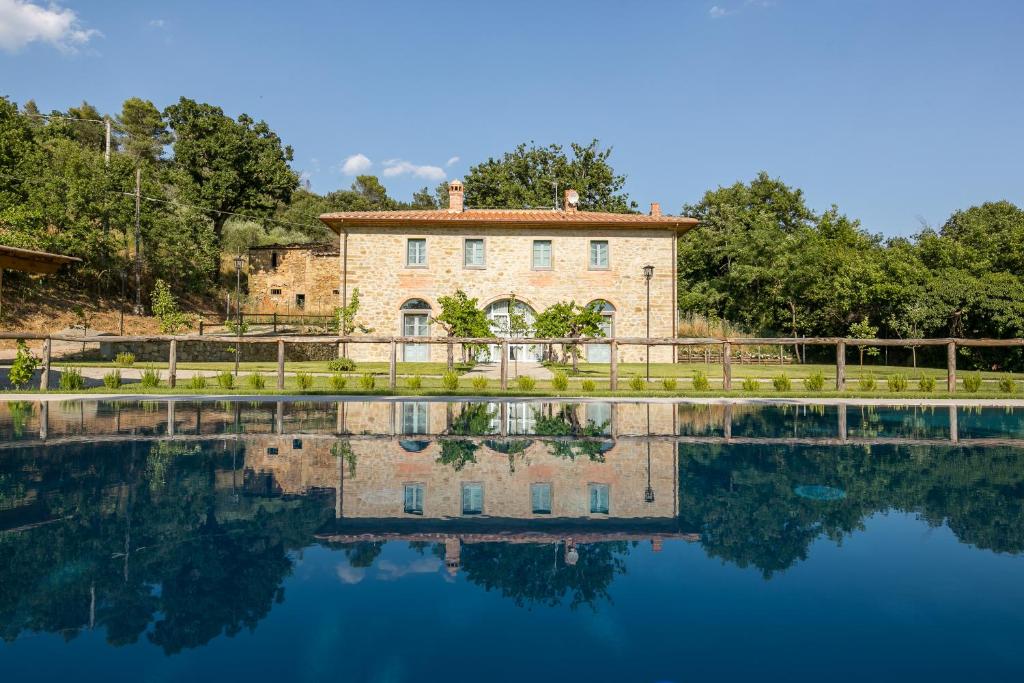 une maison avec une réflexion dans l'eau dans l'établissement Villa Mezzavia, à Cortone