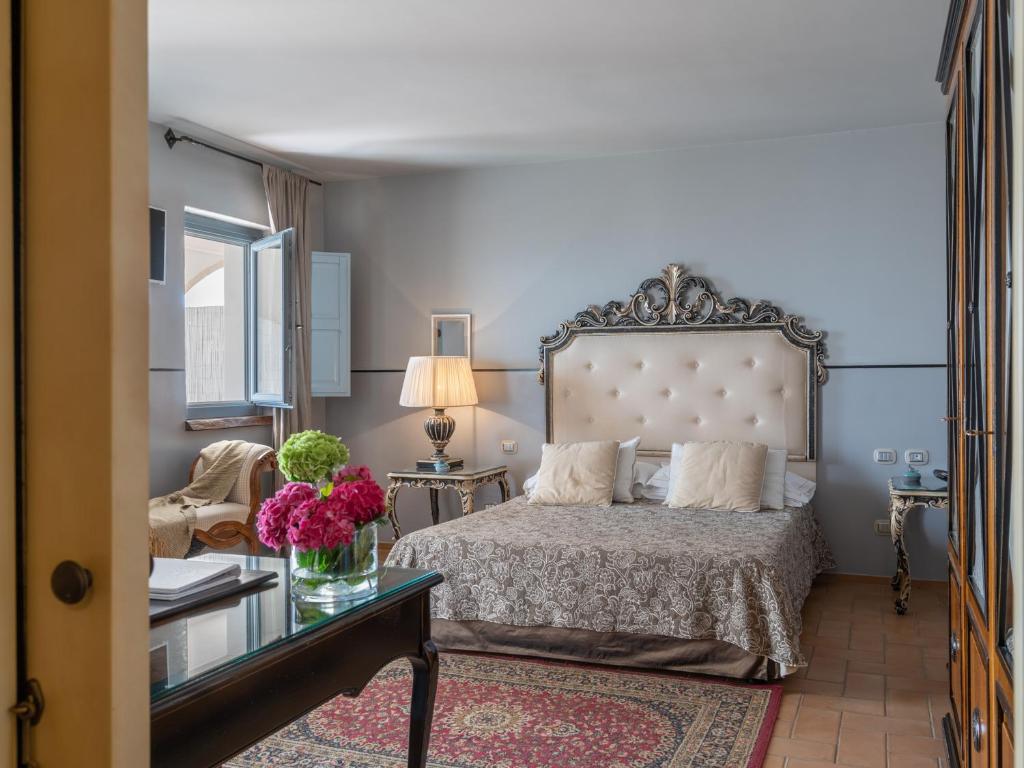une chambre avec un lit et une table avec des fleurs dessus dans l'établissement La Locanda Del Carrubo, à Mattinata 91 autres photos