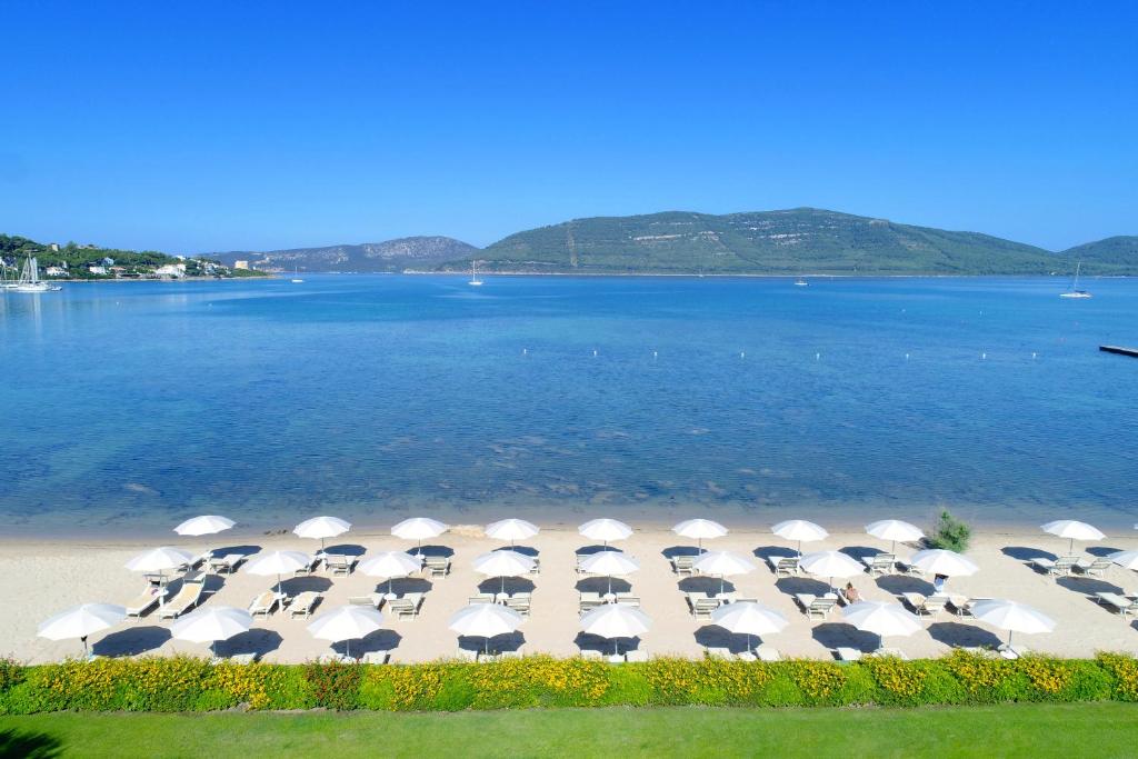 - un groupe de chaises longues avec parasols sur une plage dans l'établissement Hotel Corte Rosada Affiliated by Melia, à Porto Conte
