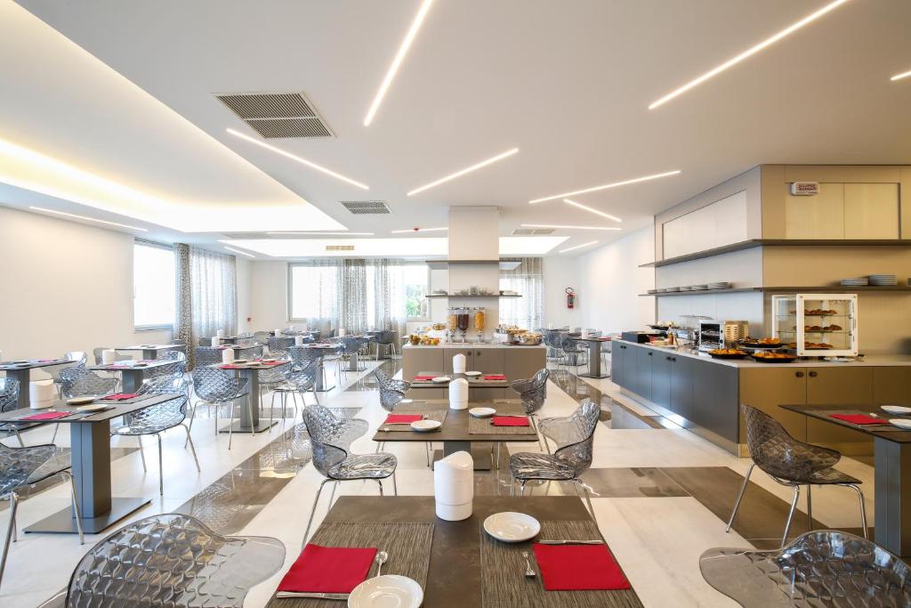 un restaurant avec des tables et des chaises et une cuisine dans l'établissement Forte 2 Hotel, à Vieste