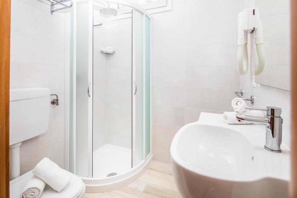 une salle de bain blanche avec une douche et un lavabo dans l'établissement Hotel Meublè Zenith, à Lignano Sabbiadoro 23 autres photos