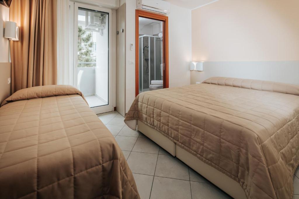 une chambre avec deux lits et une fenêtre dans l'établissement Hotel Meublè Zenith, à Lignano Sabbiadoro
