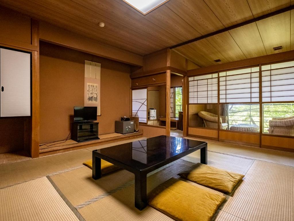 un salon avec une table et une télévision dans l'établissement Hakone Onsen Sanso Nakamura, à Hakone