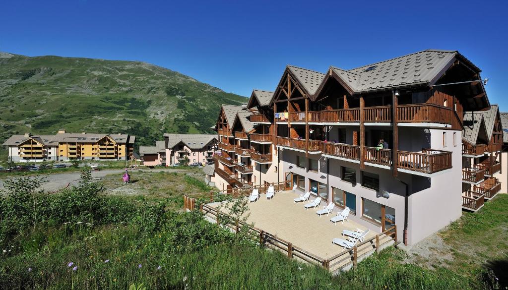 un grand bâtiment avec une terrasse et des chaises sur une colline dans l'établissement Les Hauts de Valmeinier, à Valmeinier