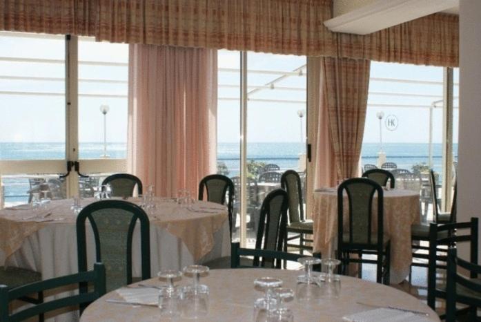 une salle à manger avec tables, chaises et fenêtres dans l'établissement Hotel Kennedy, à SantʼAlessio Siculo