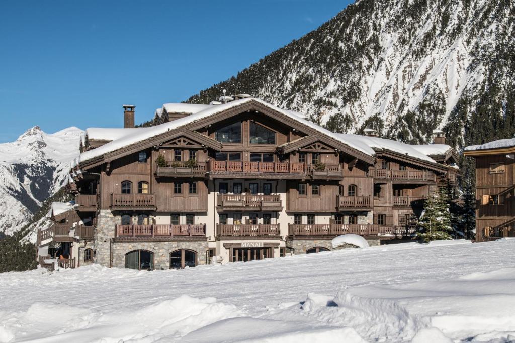un grand bâtiment dans la neige avec une montagne dans l'établissement Manali Lodge by Alpine Resorts, à Courchevel