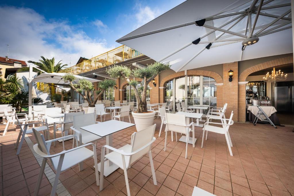 d'une terrasse avec des tables et des chaises blanches dans un restaurant. dans l'établissement Park Hotel Pineta Boutique Hotel, à Caorle