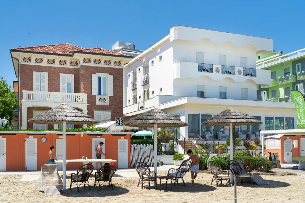 un groupe de chaises et de parasols sur une plage dans l'établissement Hotel Orizzonte, à Bellaria-Igea Marina