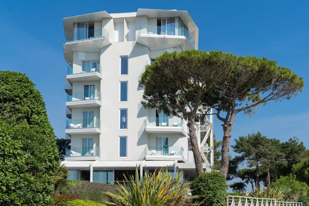un bâtiment blanc avec des arbres devant dans l'établissement Hotel Garden Sea Wellness & Spa 4 stelle superior, à Caorle