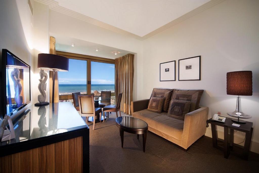 un salon avec un canapé, une télévision et une table dans l'établissement Hotel Ambasciatori, à Rimini