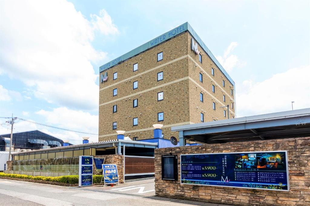 un bâtiment avec une enseigne devant lui dans l'établissement Water Hotel Mw (Love Hotel), à Saitama