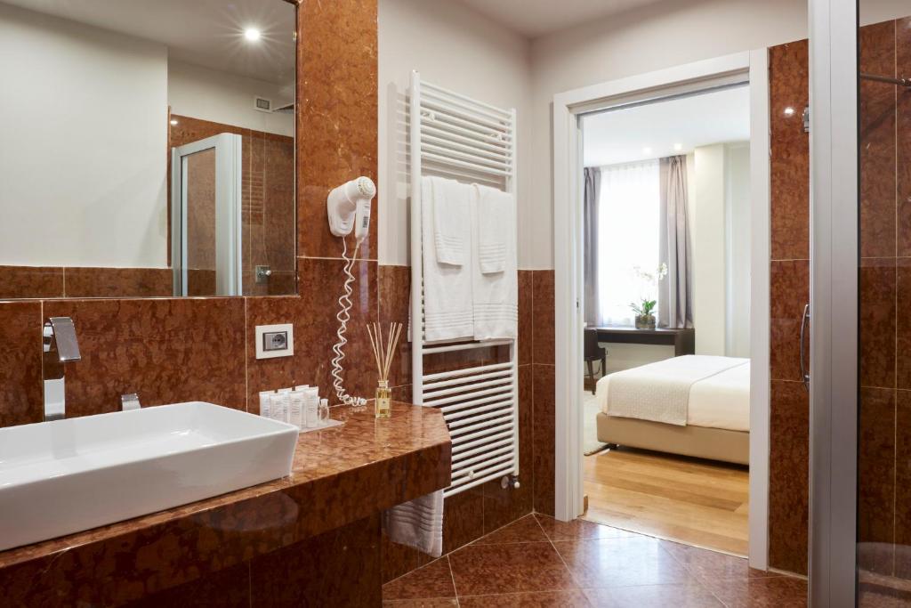 une salle de bain avec un lavabo et un lit dans l'établissement Hotel Michelangelo, à Carrara