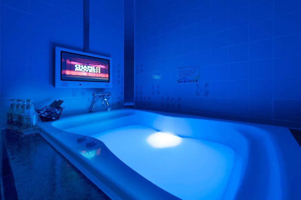 Cette chambre dispose d'une télévision et d'une baignoire bleue. dans l'établissement ホテル ロコガーデン 小牧, à Toyoyama