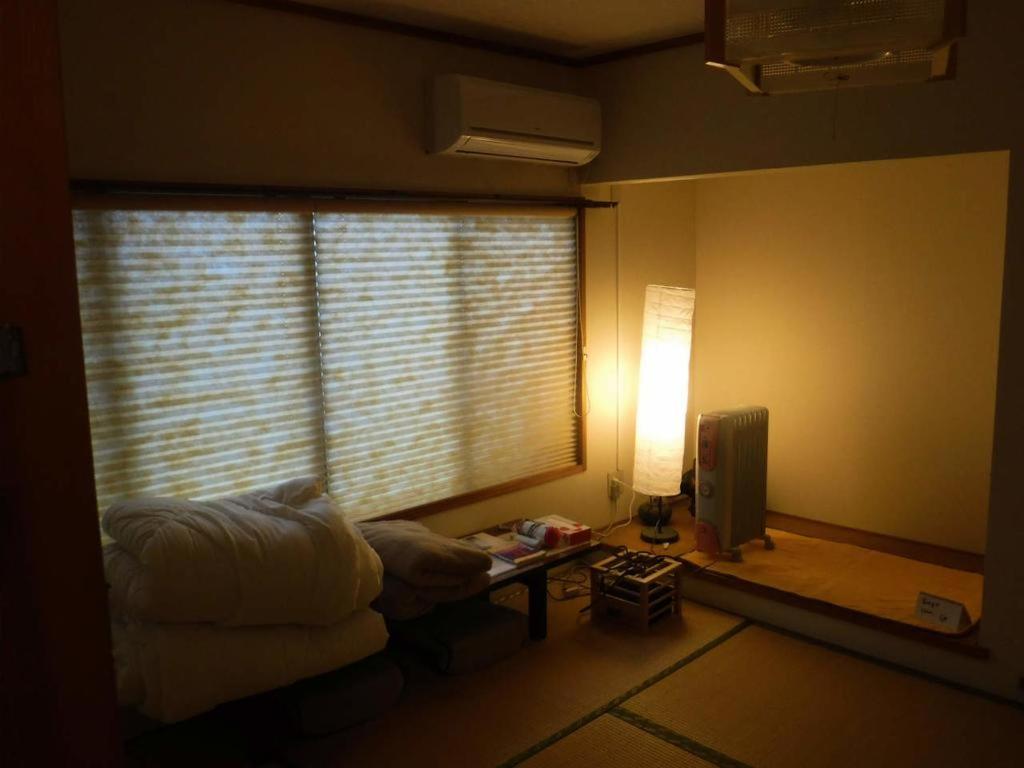 un salon avec une fenêtre, une table et une lampe dans l'établissement Wholeearth Ryokan Hiroshima, à Hiroshima