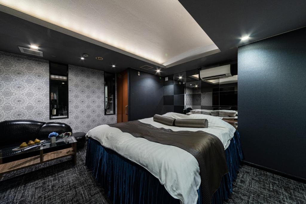 une chambre avec un grand lit et un canapé dans l'établissement Hotel Aqua Kiss Moriyama (Adult Only), à Moriyama