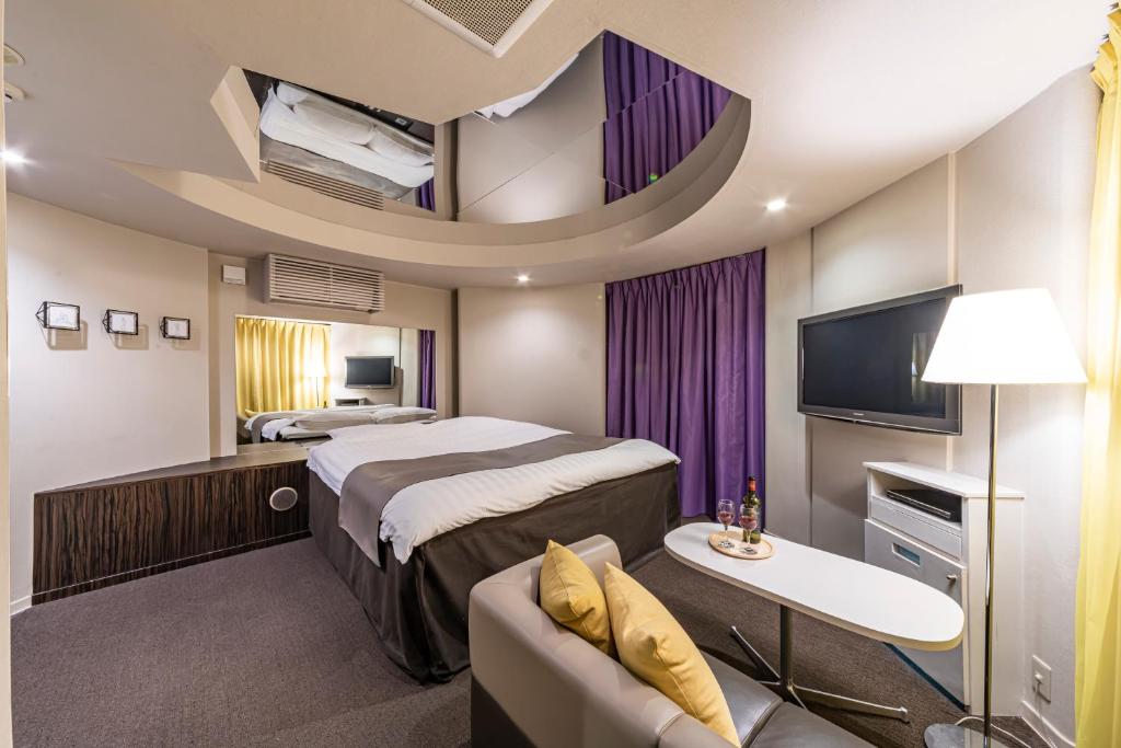 une chambre d'hôtel avec un lit et un canapé dans l'établissement Hotel Aqua Kiss Moriyama (Adult Only), à Moriyama