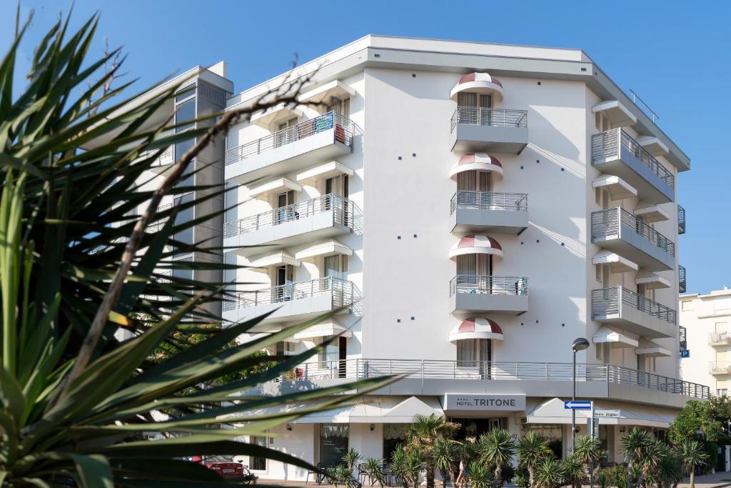 - un immeuble d'appartements blanc avec balcon et palmiers dans l'établissement Hotel Tritone, à Caorle