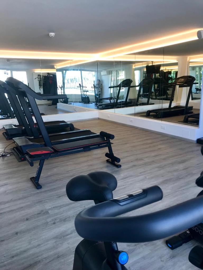 - une salle de sport avec une rangée de chaises et de miroirs dans l'établissement Hotel Tritone, à Caorle
