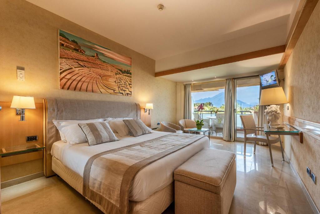 une chambre avec un grand lit et un balcon dans l'établissement Acacia Resort Parco Dei Leoni, à Campofelice di Roccella