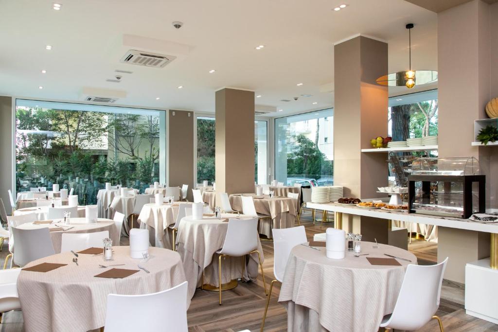 un restaurant avec des tables blanches et des chaises blanches dans l'établissement Hotel Greif, à Lido di Jesolo 30 autres photos