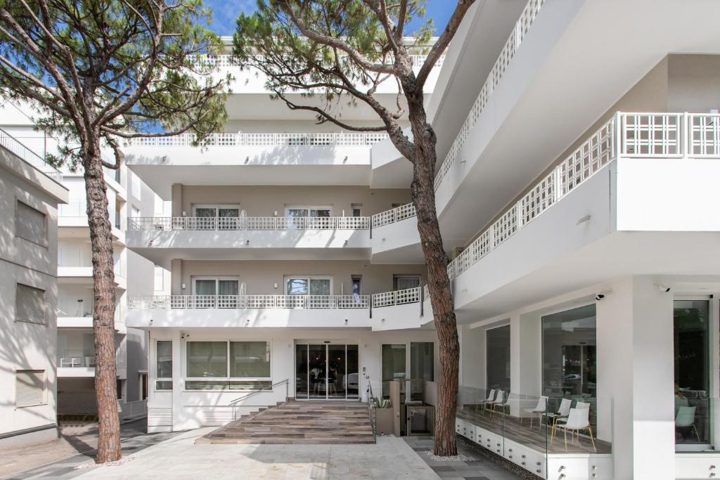 une vue extérieure d'un bâtiment blanc avec des arbres dans l'établissement Hotel Greif, à Lido di Jesolo