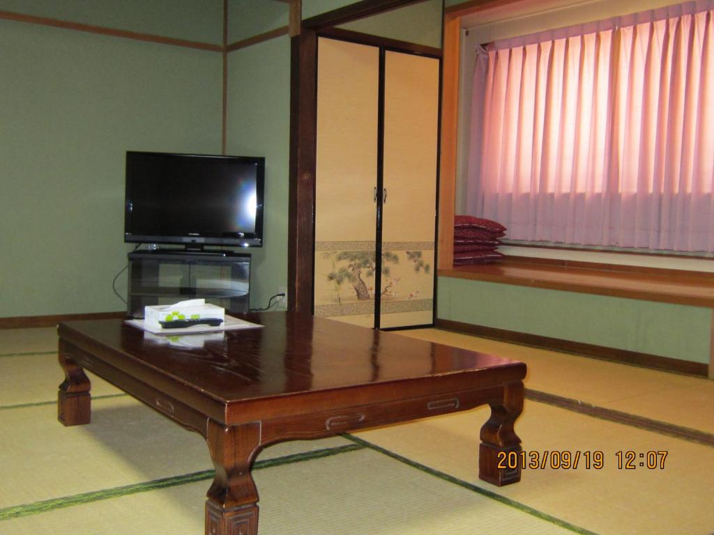 - un salon avec une table basse et une télévision dans l'établissement Takaraya, à Kotohira