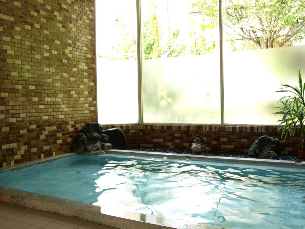 une grande piscine dans un immeuble avec des fenêtres dans l'établissement Maruni Ryokan, à Hakuba