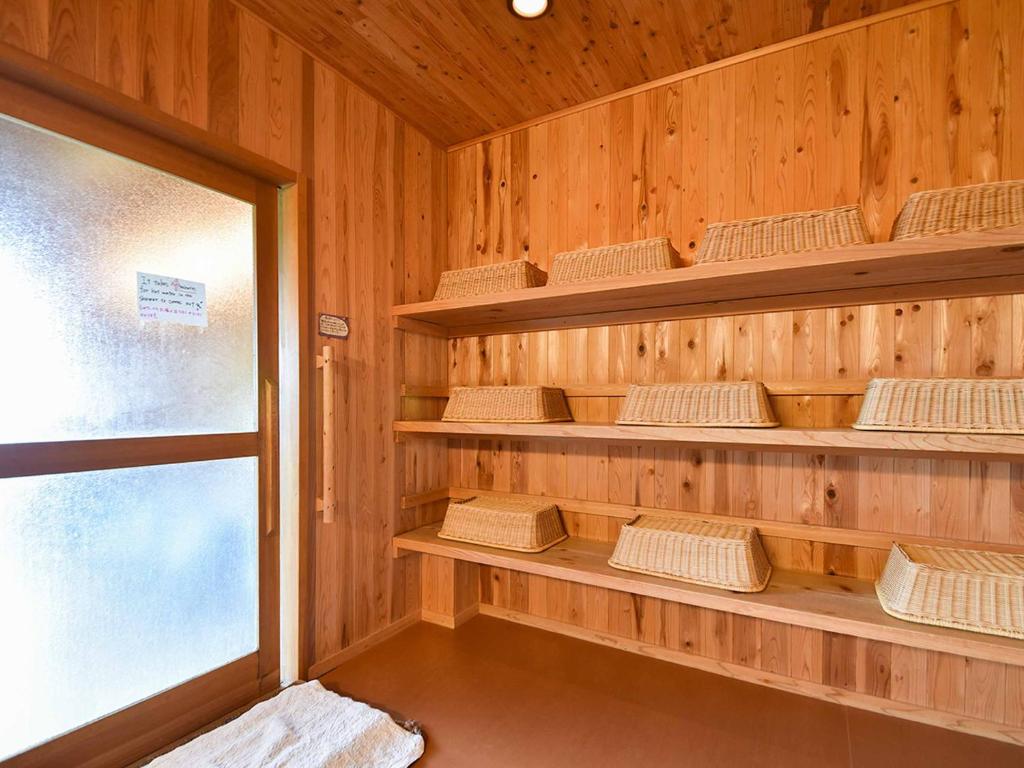 un sauna avec des murs et des étagères en bois et une fenêtre dans l'établissement Kirinosato Takahara, à Tanabe