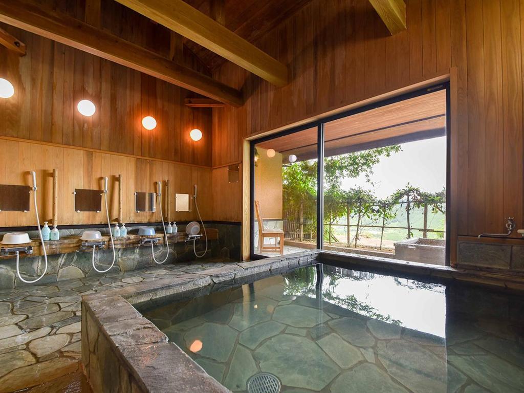 une piscine dans une salle de bain avec une grande fenêtre dans l'établissement Kirinosato Takahara, à Tanabe