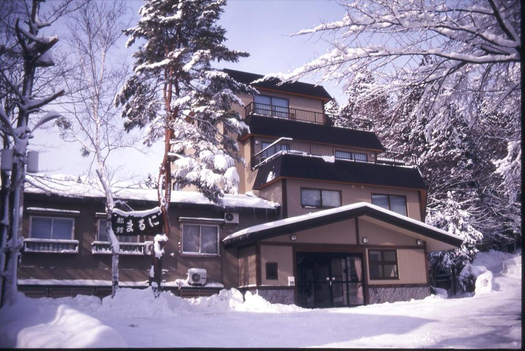 une maison avec de la neige devant elle dans l'établissement Maruni Ryokan, à Hakuba